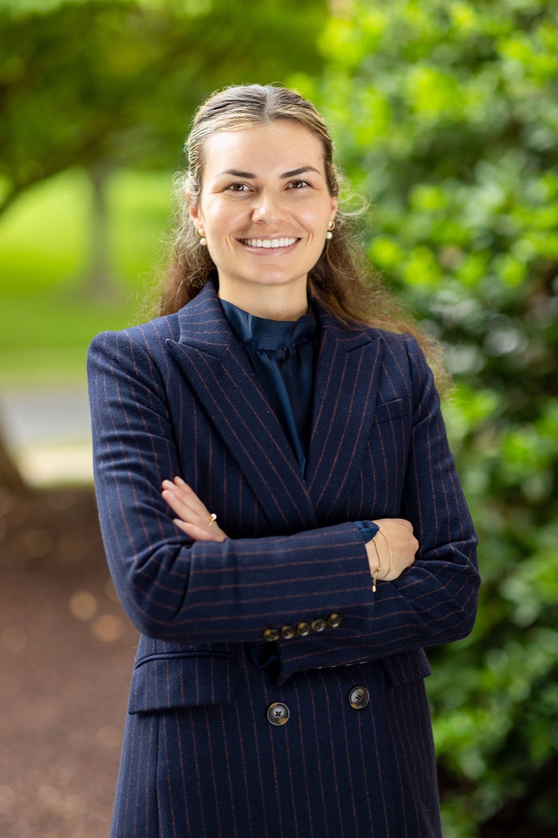 Sam Stadnik, smiling, in a navy pinstripe blazer outdoors